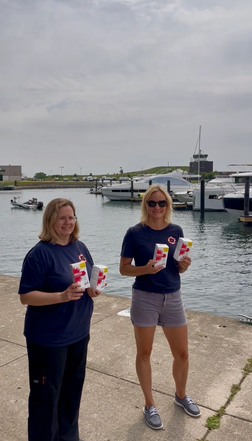 Two women holding drinks by the marina.