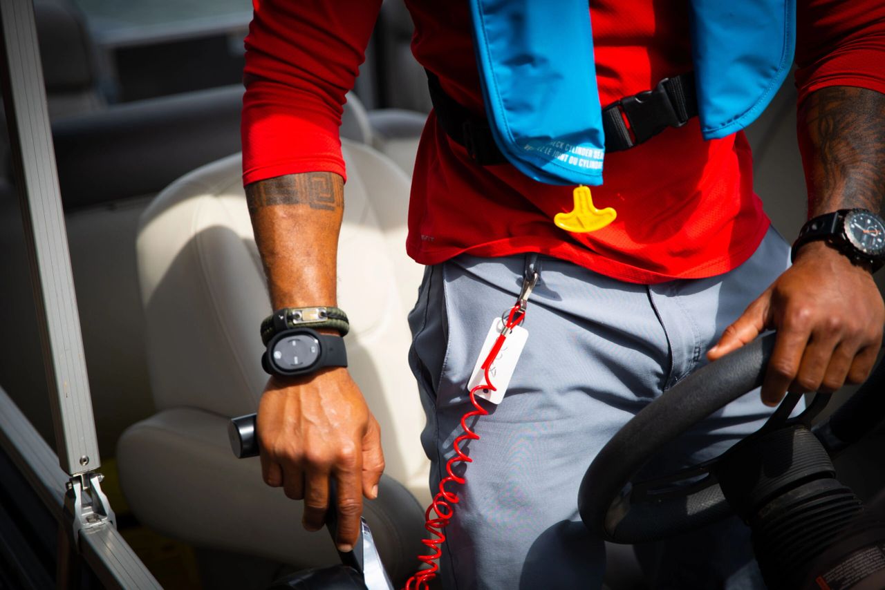 Close-up of hands on boat steering wheel.