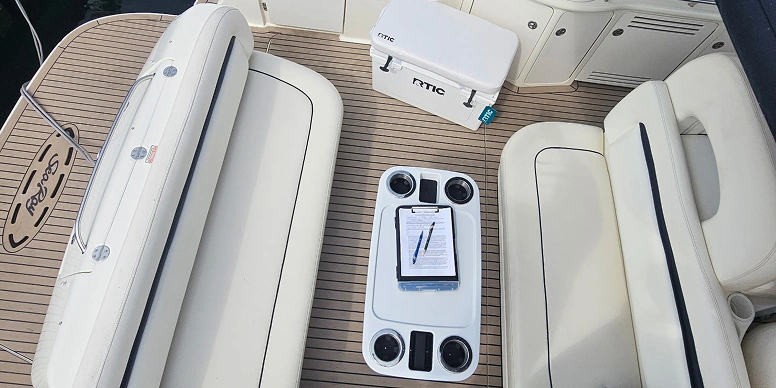 Boat with two seats and a table on the deck, with a tablet computer sitting on top of it