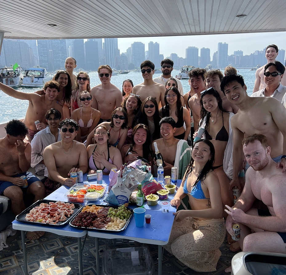 Group of people sitting around a table on a boat, enjoying a picnic