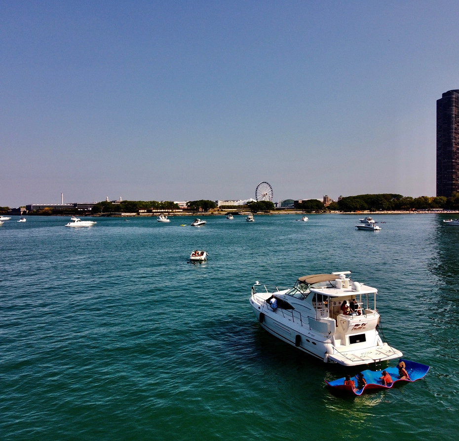 Group of boats floating on top of a body of water, with people in the boats