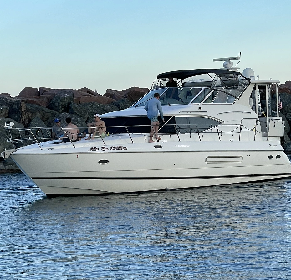 White boat with people on it in the water, surrounded by rocks and a clear blue sky