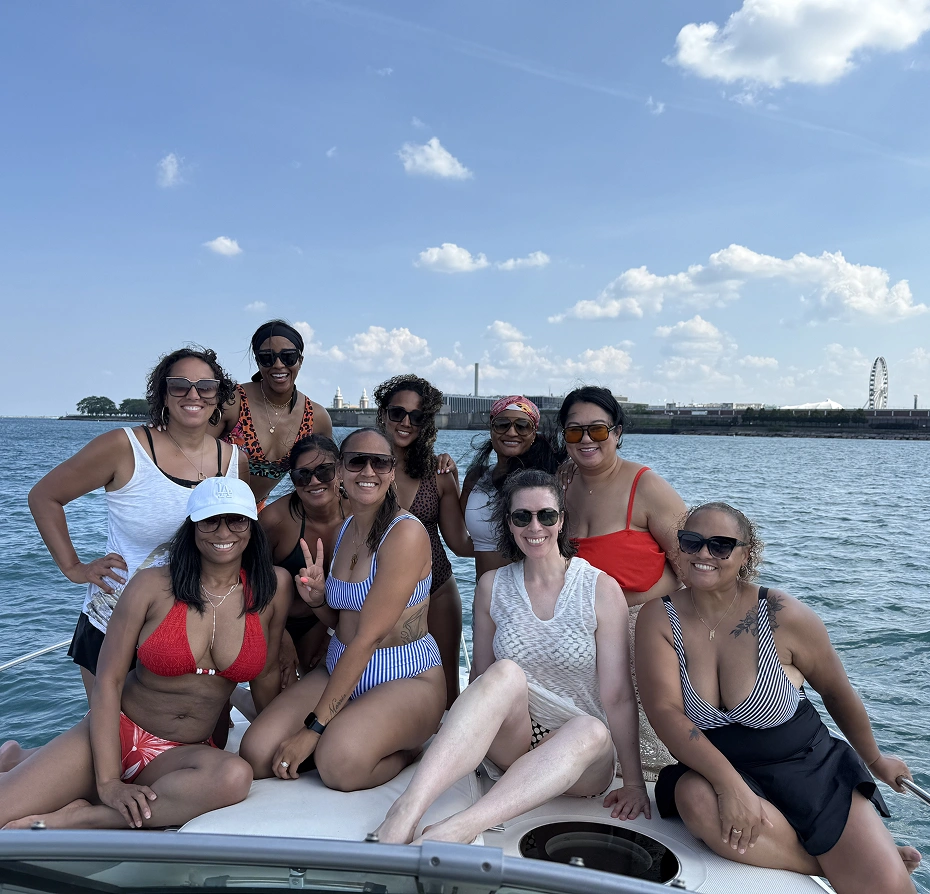 Group of women in bikinis sitting on top of a boat, and enjoying a boat ride in the water