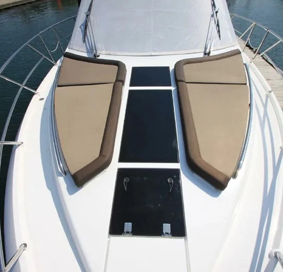 White boat with two seats on the deck, surrounded by water and a bridge in the background