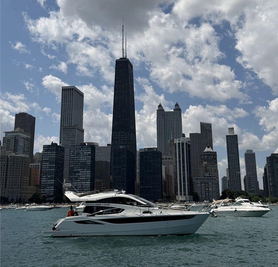 Group of boats floating on top of a body of water, with the iconic Chicago skyline in the background