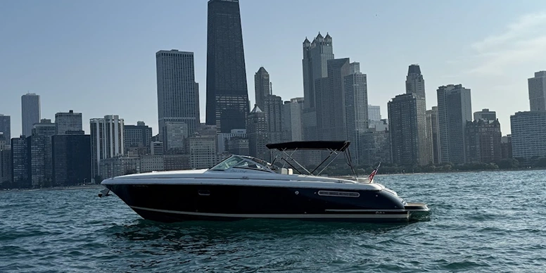 Black and white boat traveling down a river with a Chicago skyline in the background
