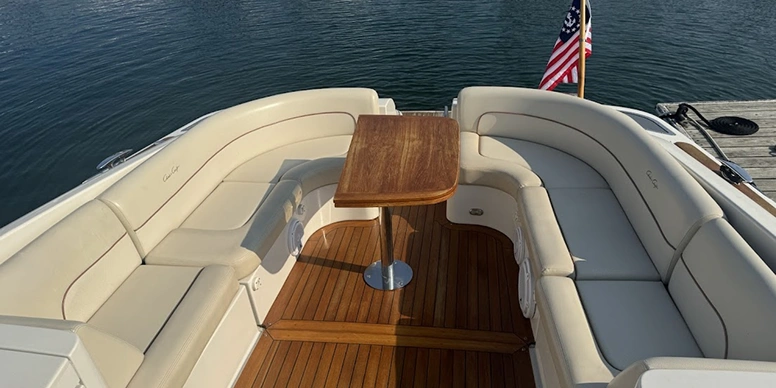 Boat with a wooden table on the deck, surrounded by a wooden fence and a flagpole