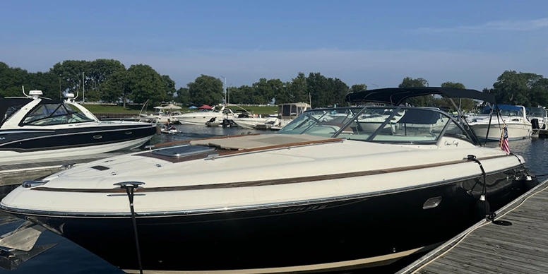 Black and white 260 Sundancer boat docked at a dock surrounded by other boats on the water