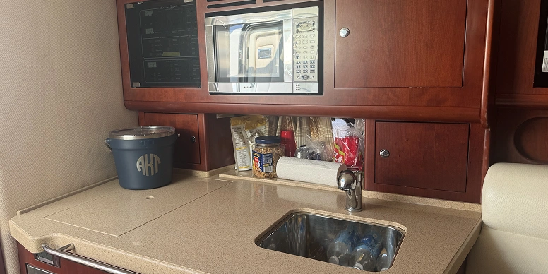 Kitchen with a sink, tap, microwave oven, cupboards, utensils, and other objects