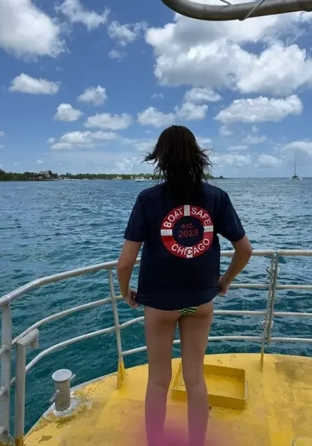 Woman standing on the deck of a boat in the ocean, wearing a t-shirt