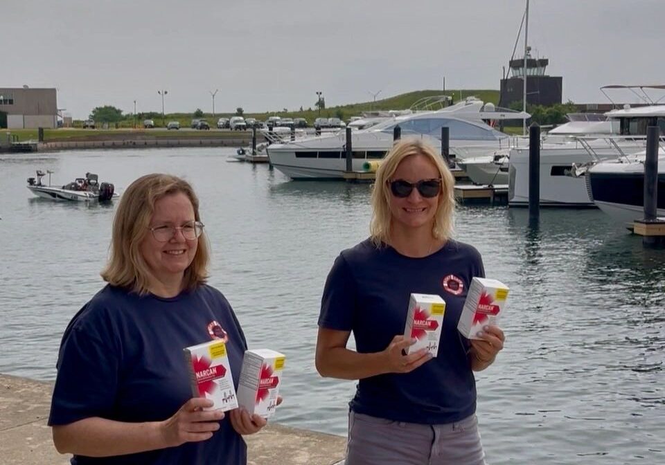 Two women holding drinks by the marina.