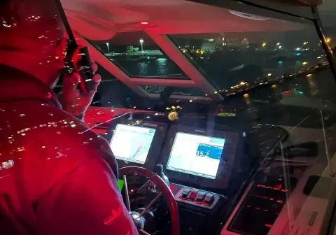 Man steering yacht with red lights