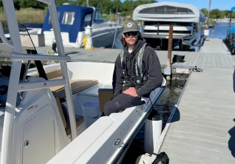 Boater wearing a life jacket beside docked motorboats
