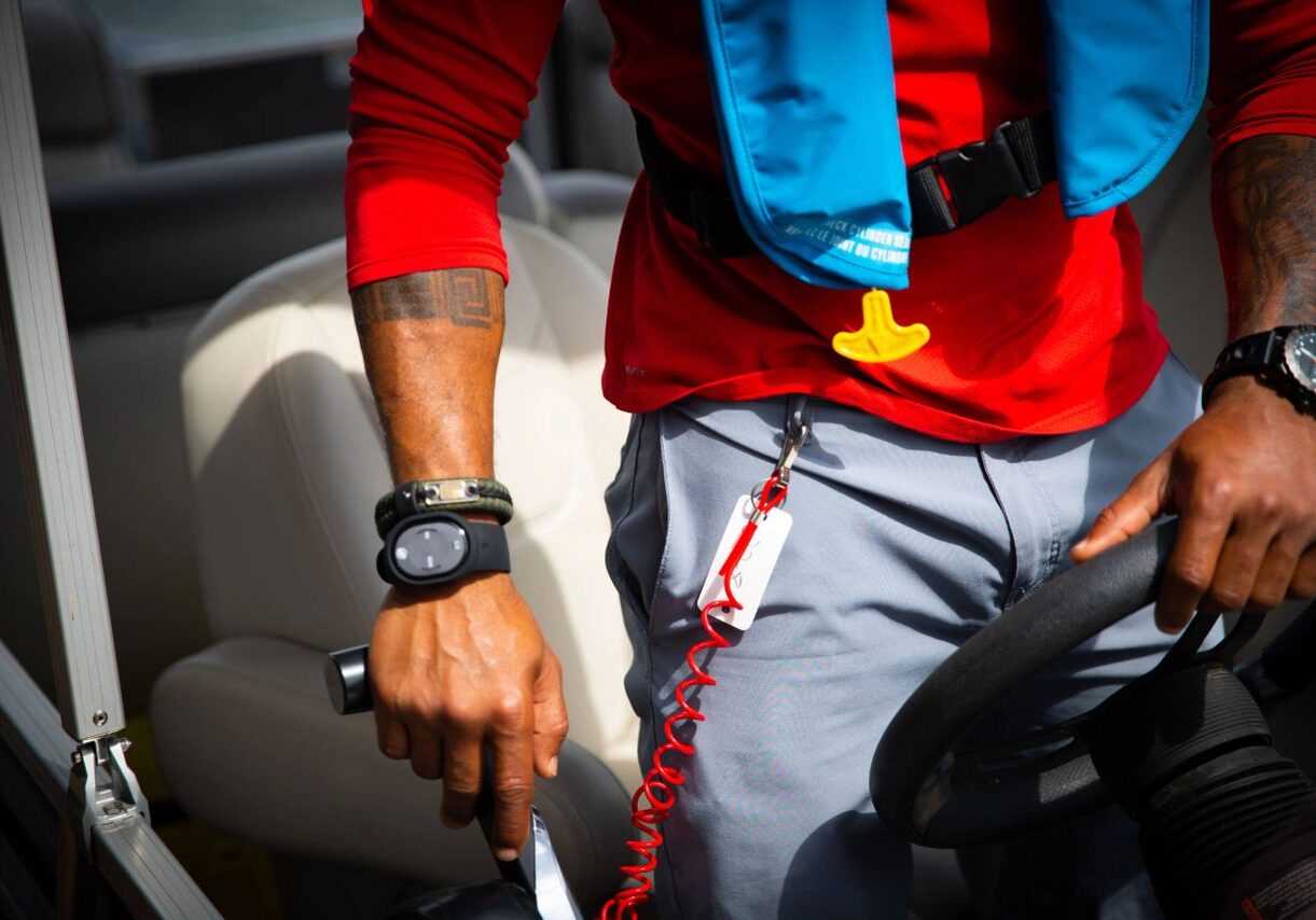 Close-up of hands on boat steering wheel.