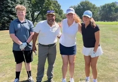 Four golfers posing together on a golf course
