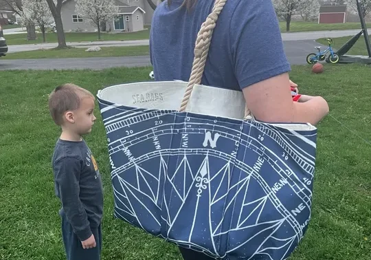 Woman carrying a navy tote bag decorated with sailboat rigging